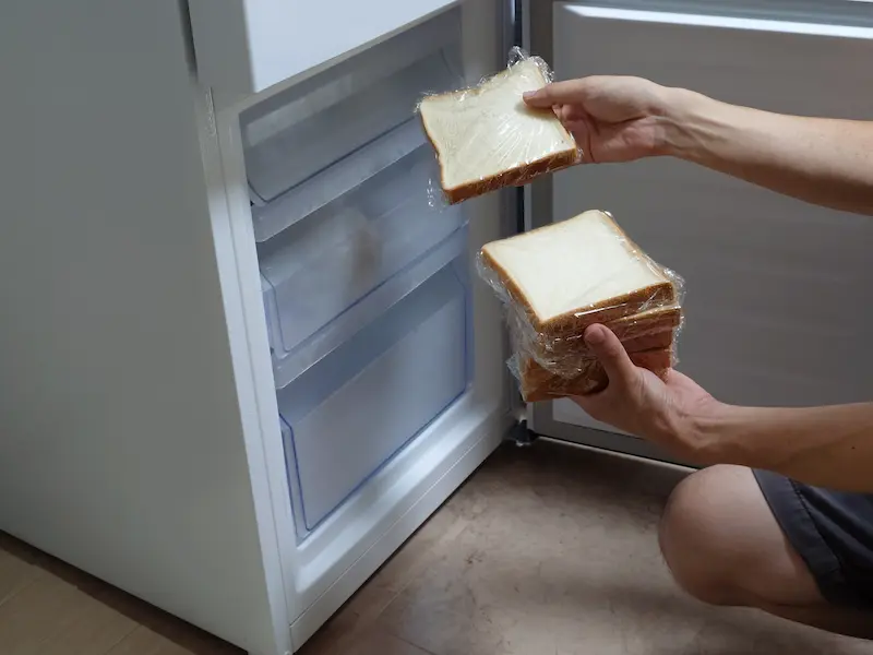 ラップに包んだ食パンを冷蔵庫に収納している画像